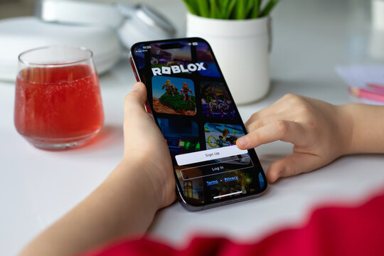 Children hands holding iPhone 15 Pro Max with game Roblox