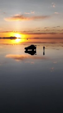 Salar de Uyuni in Bolivia during sunset. Aerial image taken with a drone. Uyuni Salt Flats. Altiplano, Bolivia. Rainy Season. Tunupa Volcano. Clouds Reflection on Water in Lake Surface. Vertical video