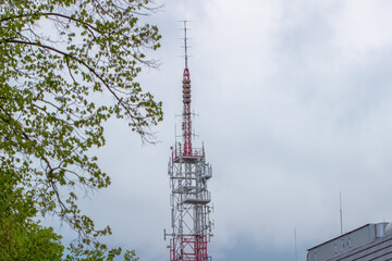 cell phone and television tower against the background of a building and trees, view from below...
