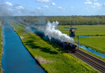 train on the river passing a windmill in holland