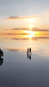 Salar de Uyuni in Bolivia during sunset. Aerial image taken with a drone. Uyuni Salt Flats. Altiplano, Bolivia. Rainy Season. Tunupa Volcano. Clouds Reflection on Water in Lake Surface. Vertical video