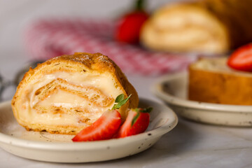 Sliced rolls with custard. The dessert is decorated with fresh strawberries
