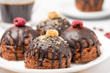 Round chocolate cakes. Decorated with candied raspberries. Light background