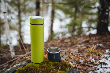 Camping utensils, thermos with a mug on the background of the autumn forest, camping utensils,...