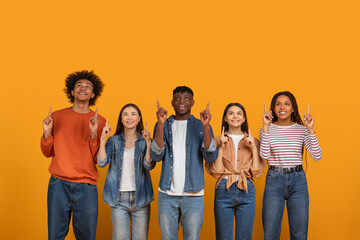 Diverse group of people pointing up on orange background
