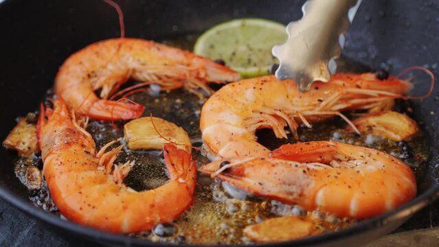 Pan with grilled prawn shrimps with garlic lime tomatoes and spices, chef cooking asian traditional thai food, wok restaurant.