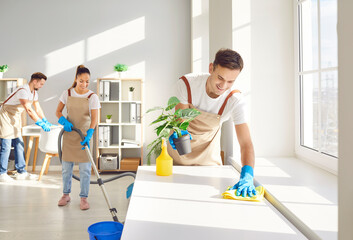 Male top performing cleaner and happy team cleaning room. Group sanitizing home, dust surface,...