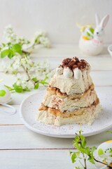 Dessert, cottage cheese Easter in the style of tiramisu with cottage cheese cream and cookies on a ceramic plate on a light concrete background. World holidays
