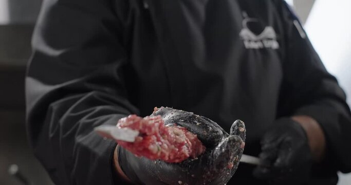 Adana kebab preparation. Chef shapes Turkish kebab, spreads ground meat along the skewer using hands. Grilling on barbecue charcoal grill. Oriental cuisine. Close-up