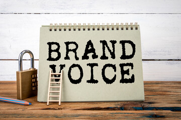 Brand Voice. Green notepad on wooden texture table and white background - 792001328