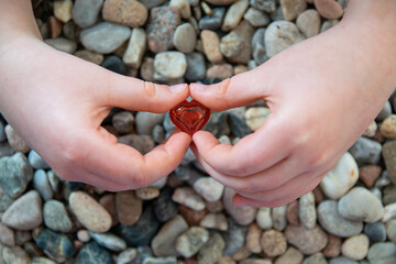 Red heart shape in hand on the stone background.