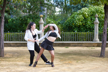 Couple of young women dancing to latin music: Bachata, merengue, salsa. The two girls do different...