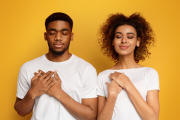Kind woman and man keep both palms on chest