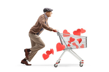 Full length profile shot of an elderly man running and pushing a shopping cart with red hearts