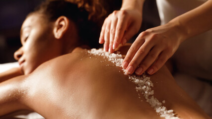 Woman receiving a salt scrub treatment at spa