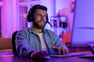 Bearded man using a headset at the computer - obrazy, fototapety, plakaty