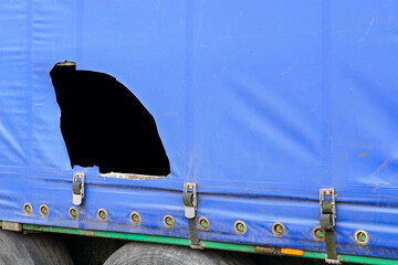 Truck trailer with blue damaged awning, cargo goods theft problem by cutting the awning, cut awning