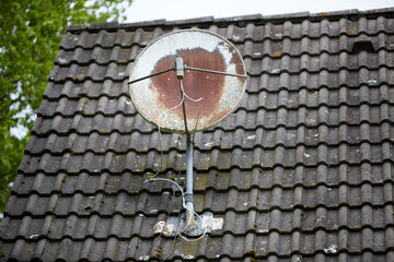 old rusty satellite dish on a house roof