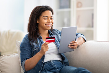 Woman Sitting on Couch Holding Credit Card and Tablet