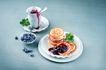Traditional American pancakes with blueberry fruits and jam served as close-up on a Nordic design...