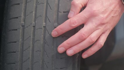 The finger indicates damage to the tire tread. Tire tread problems due to incorrect tire pressure. Worn out old tire.