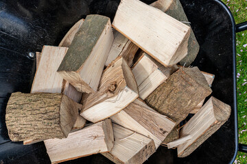 Stack of dry hard firewood split logs for fuel in a woodstove in a wheelbarrow. View from above.
