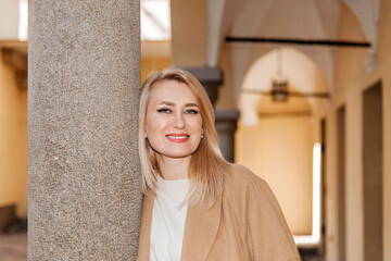 Confident Woman Leaning Against Stone Pillar in Elegant Coat