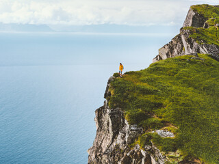 Man hiking in mountains standing on cliff edge travel solo in Norway, active healthy lifestyle...