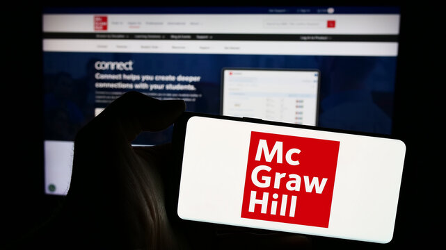 Stuttgart, Germany - 04-12-2024: Person holding mobile phone with logo of American publishing company McGraw Hill LLC in front of business web page. Focus on phone display.