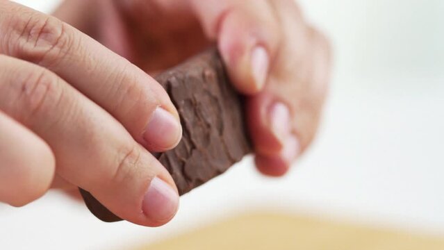 Slow motion of hands breaking a candy bar with green filling