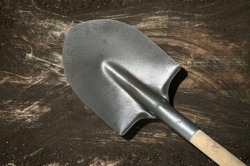 Metal shovel on dirty wooden surface, top view
