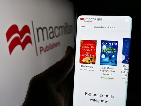 Stuttgart, Germany - 04-13-2024: Person holding cellphone with webpage of British publishing company Macmillan Publishers in front of logo. Focus on center of phone display.