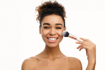 Smiling woman applying powder on face with brush tool