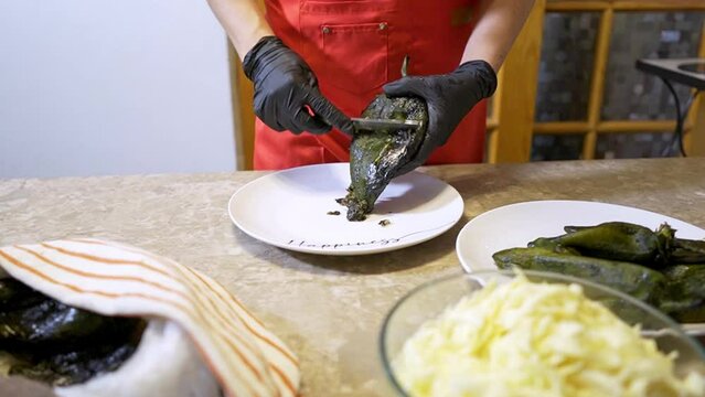 Chef cleans and removes the skin of a poblano chile to make chiles stuffed with cheese 