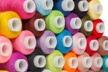multi-colored spools of sewing thread on a white background