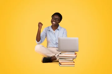 Foto op Plexiglas Happy woman with laptop sitting on books © Prostock-studio