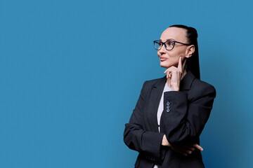Portrait of thinking serious confident business woman , on blue studio background