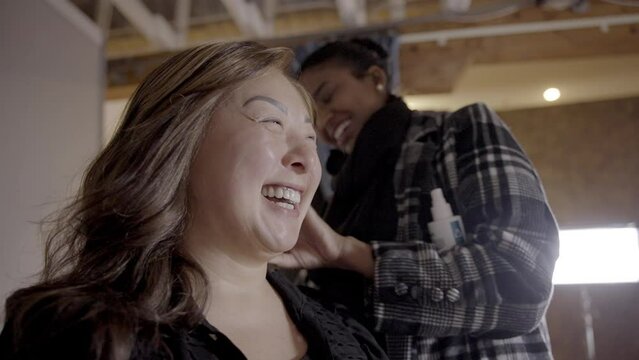 Woman wearing a wig chats with a hairdresser on set in a behind the scenes shot