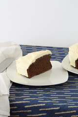 Slice of dark chocolate cake with delicate white frosting.