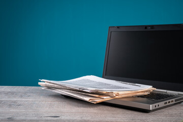 Newspapers on laptop, information, media concept, old and new sources of information