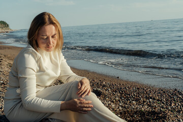 Fototapeta na wymiar Woman Sitting on Beach Next to Ocean