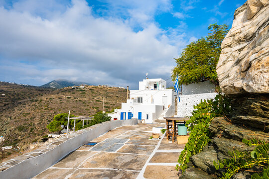 View of Kastro village buildings from coastal promenade with mountain ladscape in background, Sifnos island, Greece