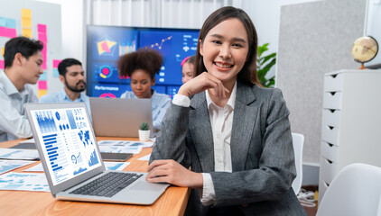 Portrait of happy young asian businesswoman with group of office worker on meeting with screen...