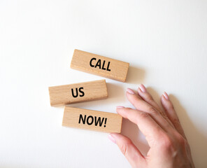 Call us now symbol. Wooden blocks with words Call us now. Beautiful white background. Businessman hand. Business and Call us now concept. Copy space.