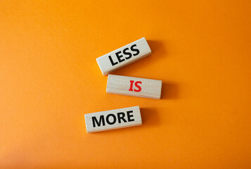 Less is More symbol. Concept words Less is More on wooden blocks. Beautiful orange background. Business and Less is More concept. Copy space.