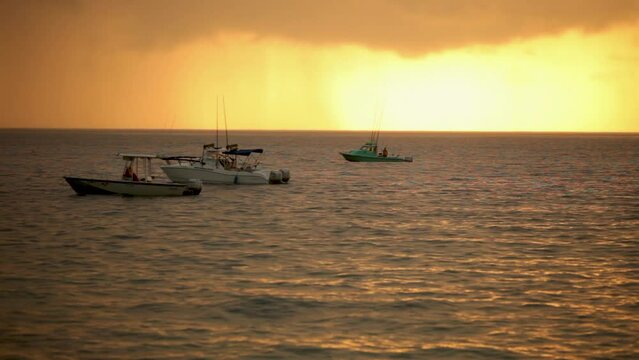 Silhouettes of boats in ocean at sunrise - wide shot