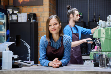 Colleagues partners young man and woman in aprons working together in coffee shop