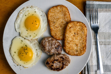 fried eggs top with parsley  with sausage and hash browns