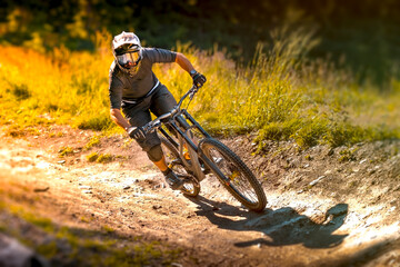 Downhill mountain biker in equipment going fast in the bike park trail.