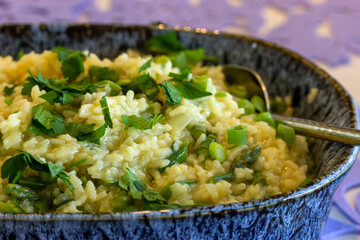 Closeup of Spring Asparagus Risotto in Blue Ceramic Bowl with Serving Spoon